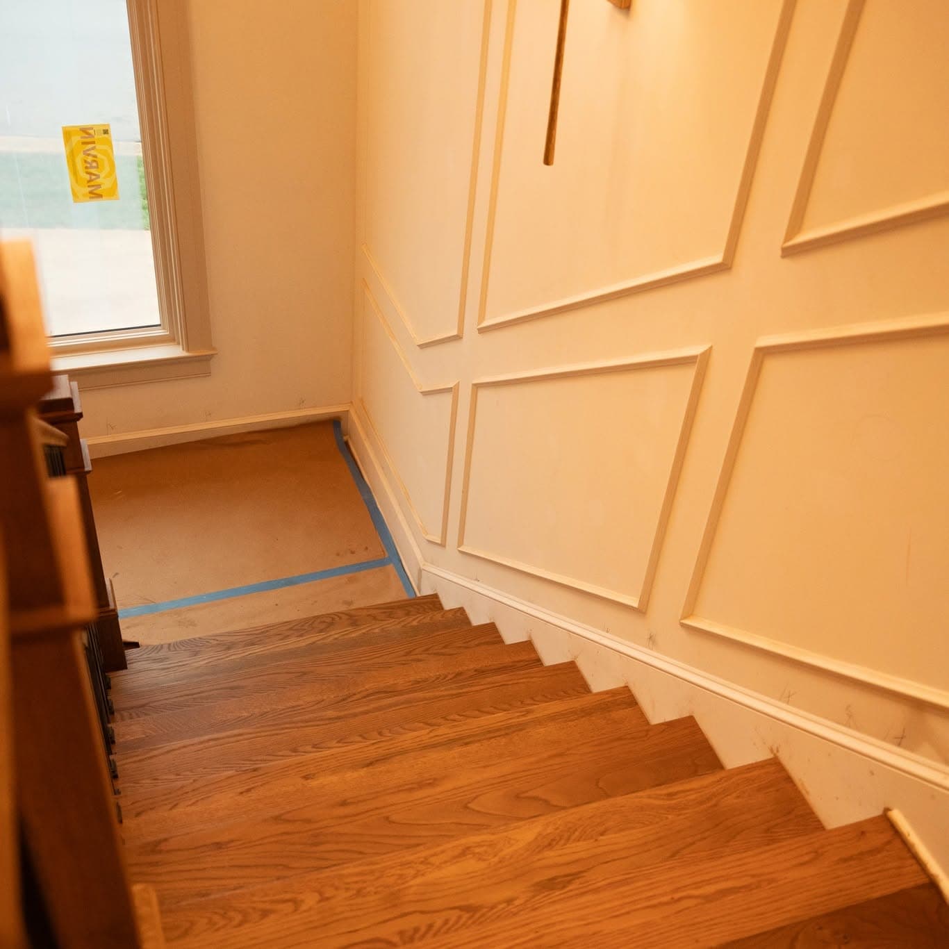 Looking down a hardwood staircase with matching oak treads and handrail, a square wood newel, and matte black metal balusters — a job by Rocket City Stairs