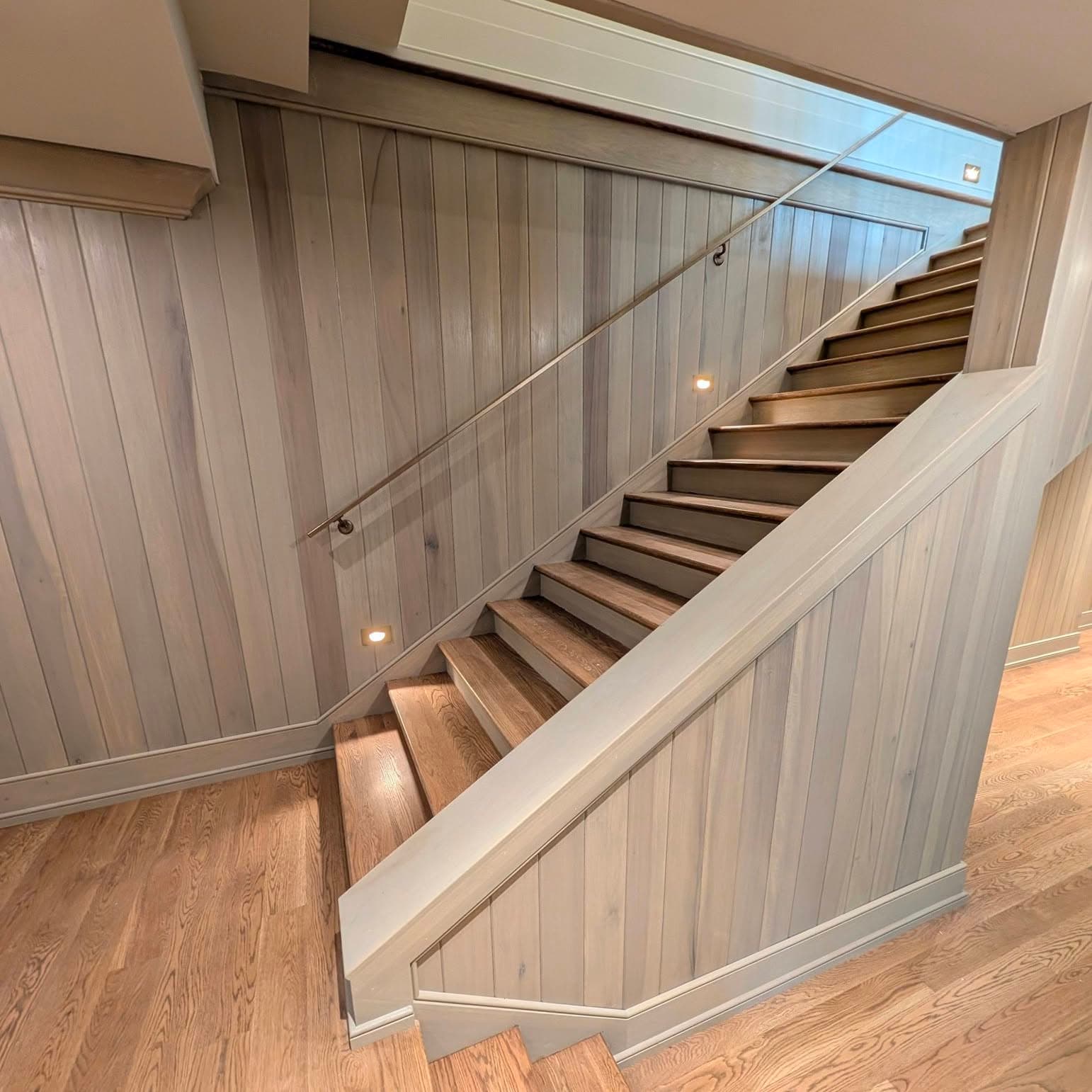 Curved/sweeping stair with painted stringer and wood handrail, hardwood landing