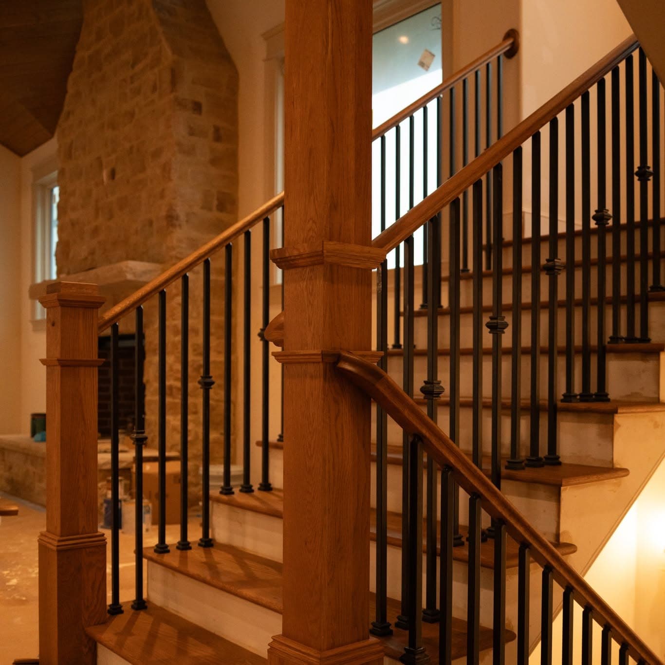 Stair beside stone accent wall, oak treads with black balusters