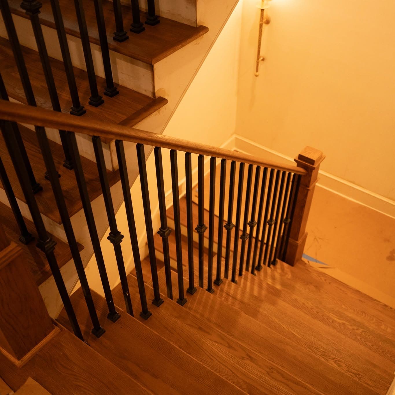 Stair run down to landing, oak treads with black balusters and sconce