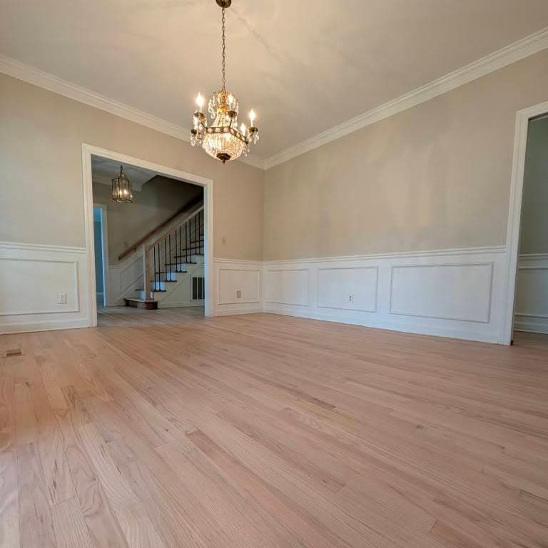 Room with wainscoting looking through doorway to stair with wood treads and black spindles