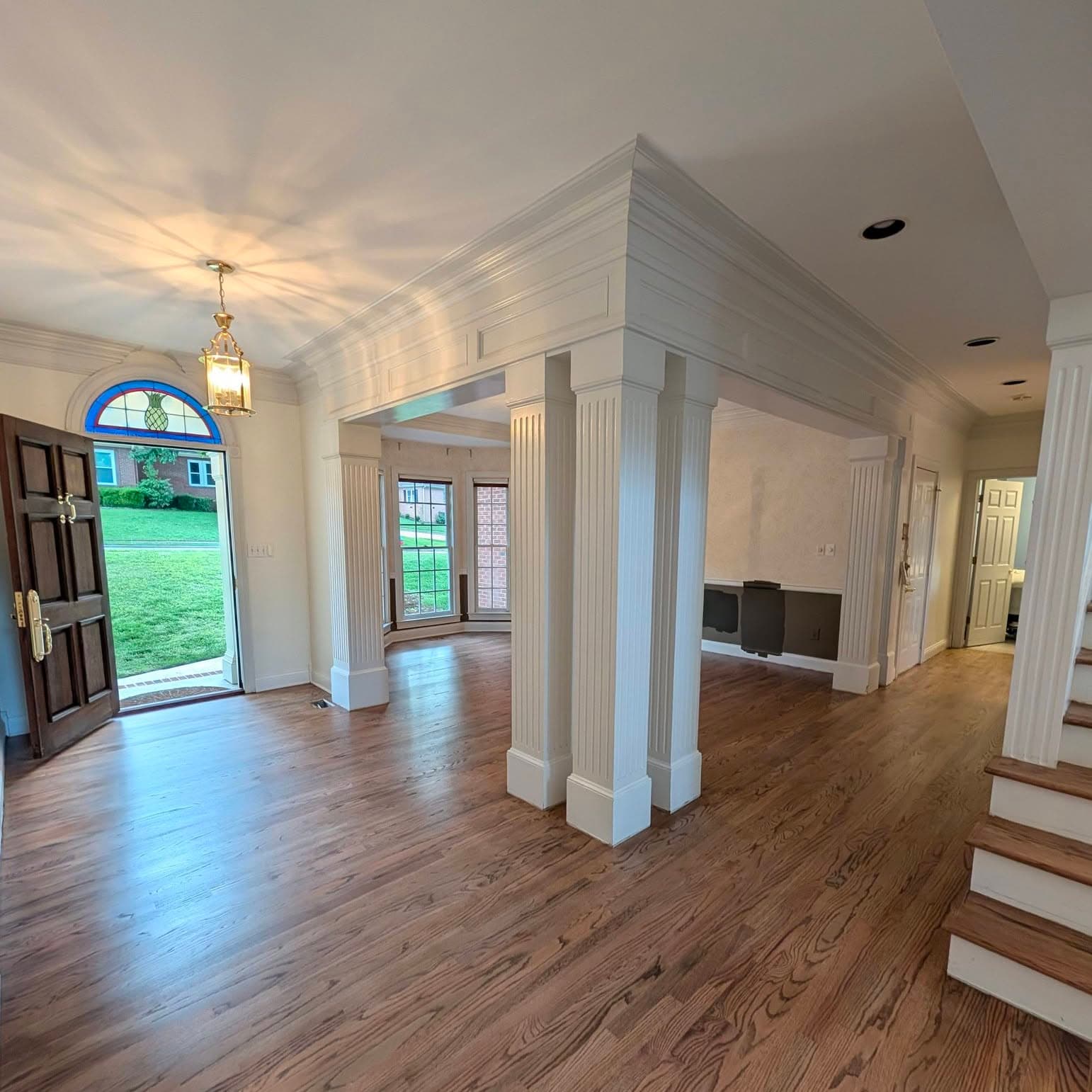 Open living space with columns; base of wooden staircase at far right