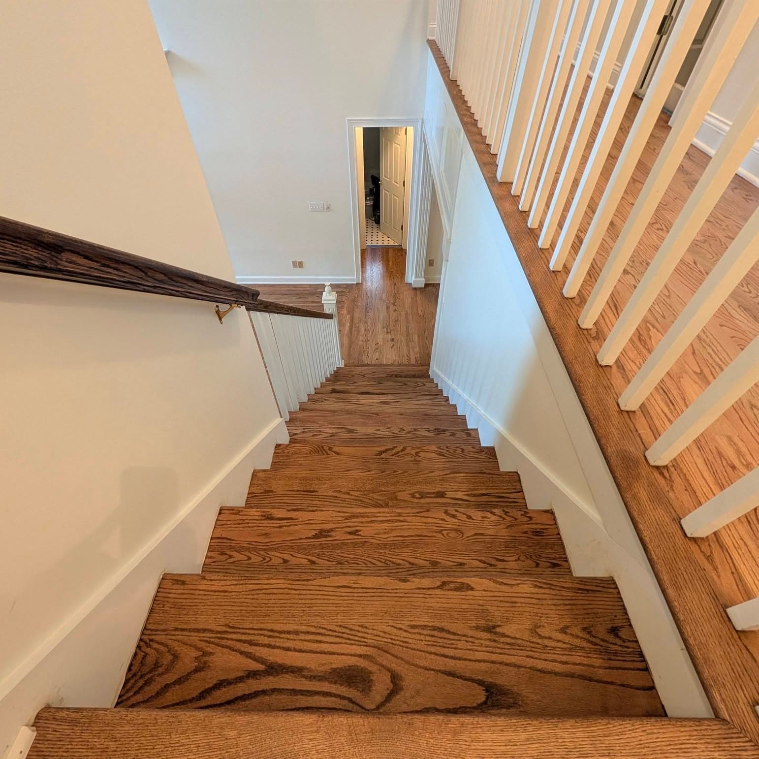 Looking down a wooden stair run with a white banister