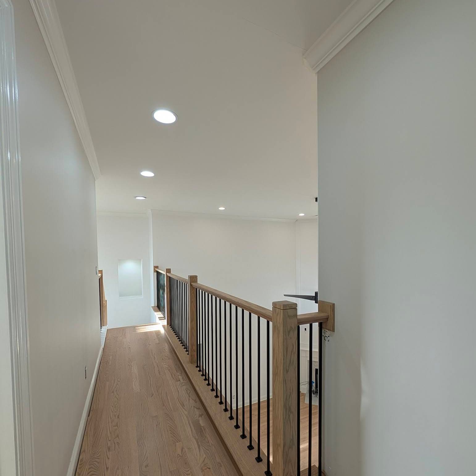 Landing/hallway railing with wood cap and black balusters overlooking lower level