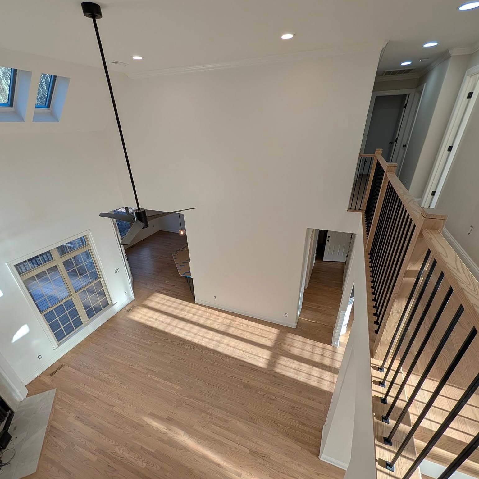 Looking down from a landing into a living room past a wooden stair railing
