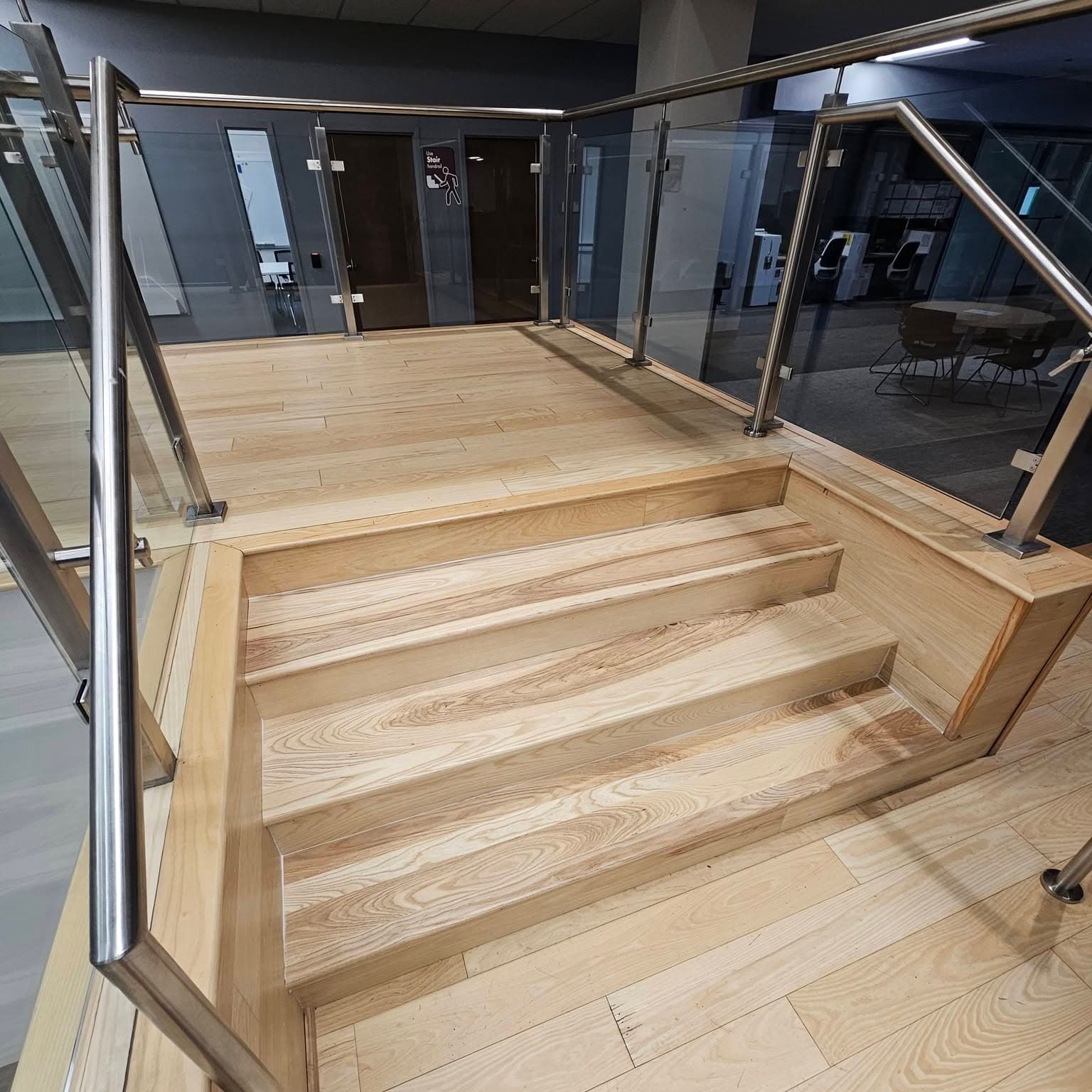 Landing and start of descent, light wood stairs with glass/metal railings