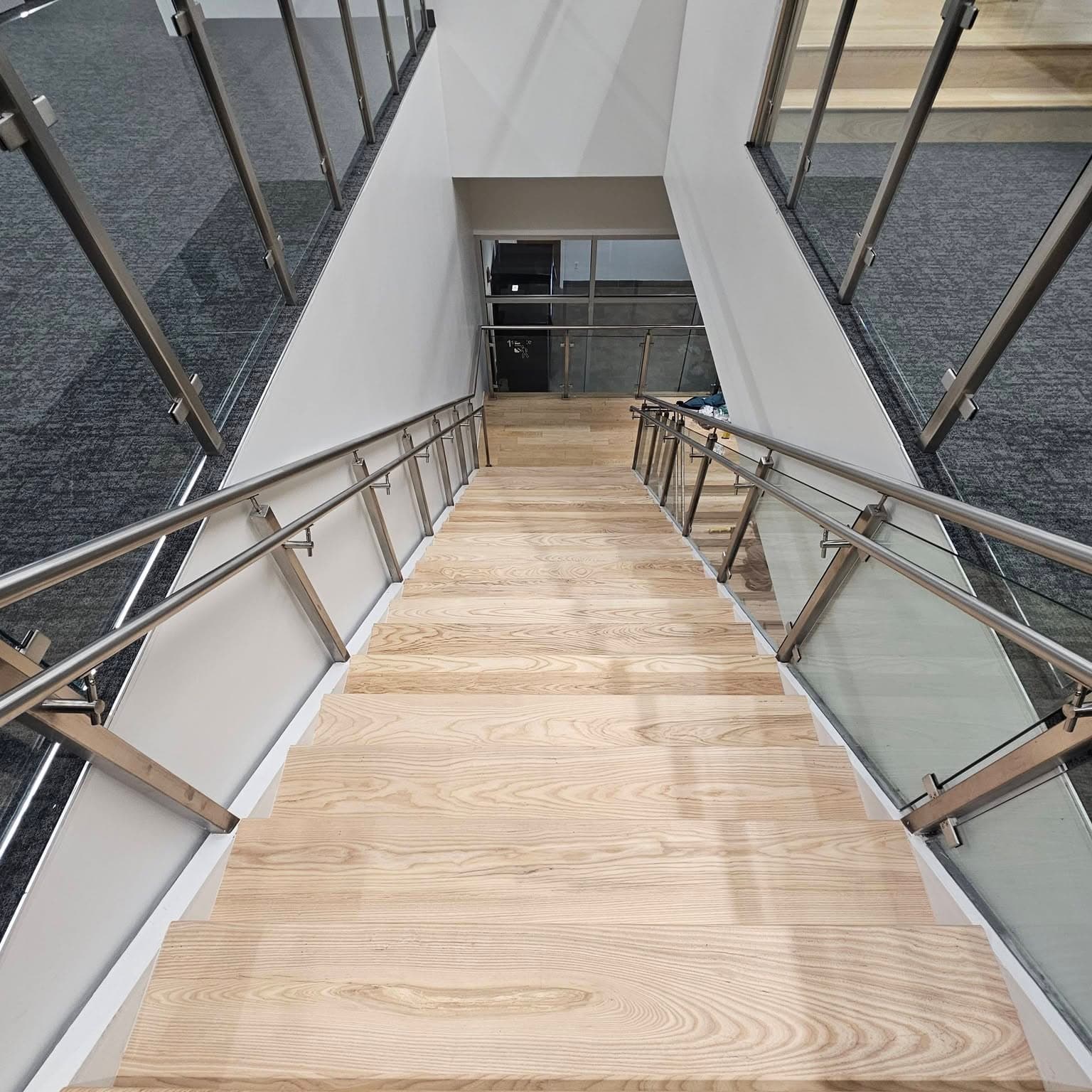 Looking down the same long light wood stair from the top