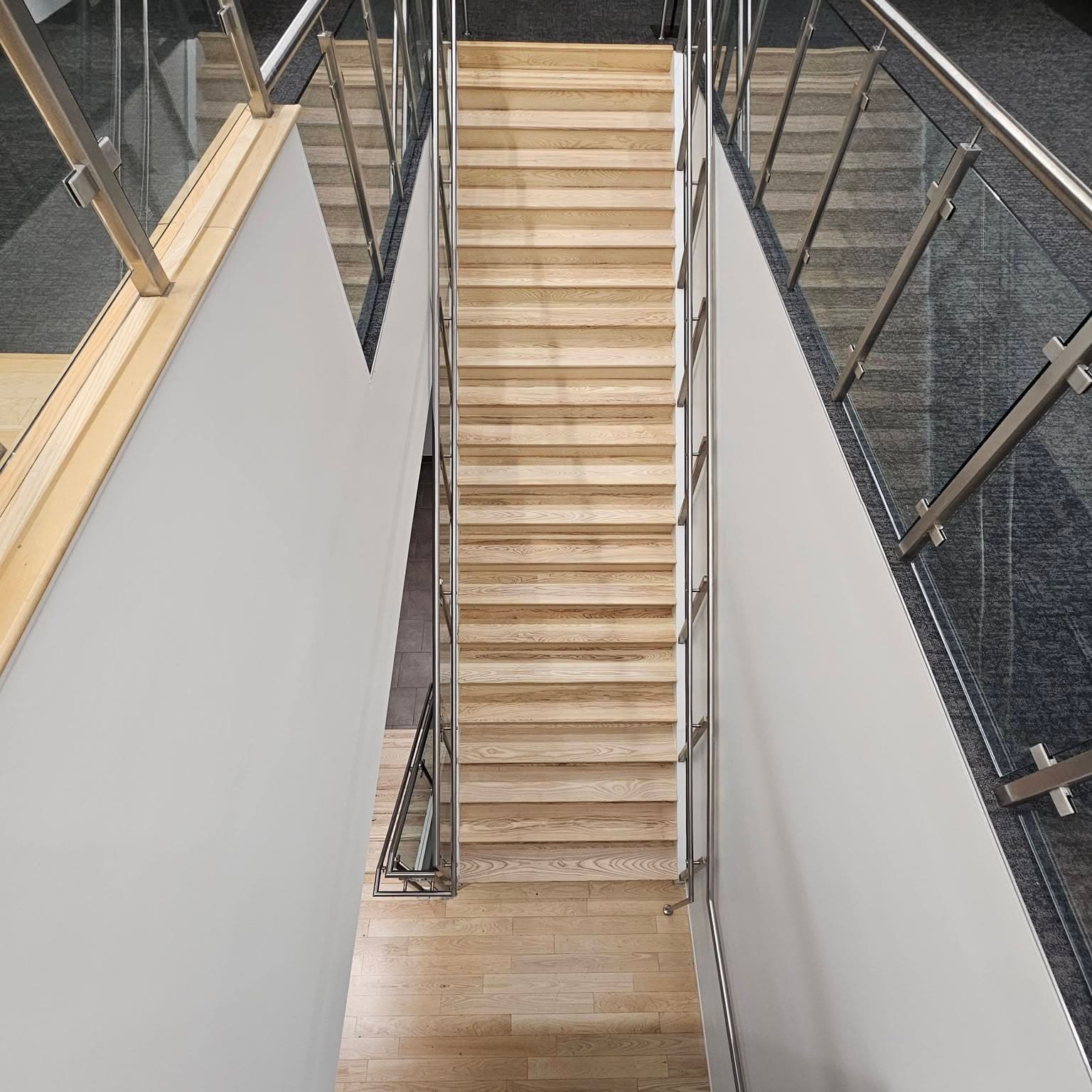 From a landing, multiple runs of a modern glass-railed staircase