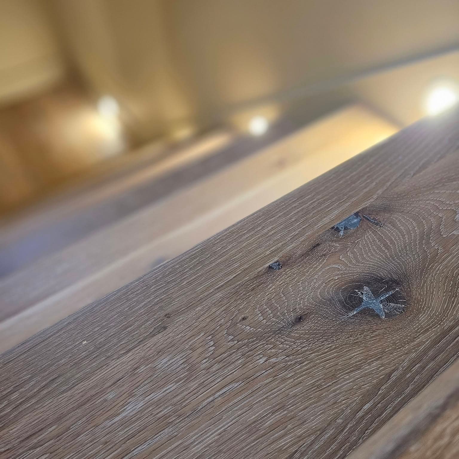 Close-up of a rustic knotted wooden stair tread with filled knots