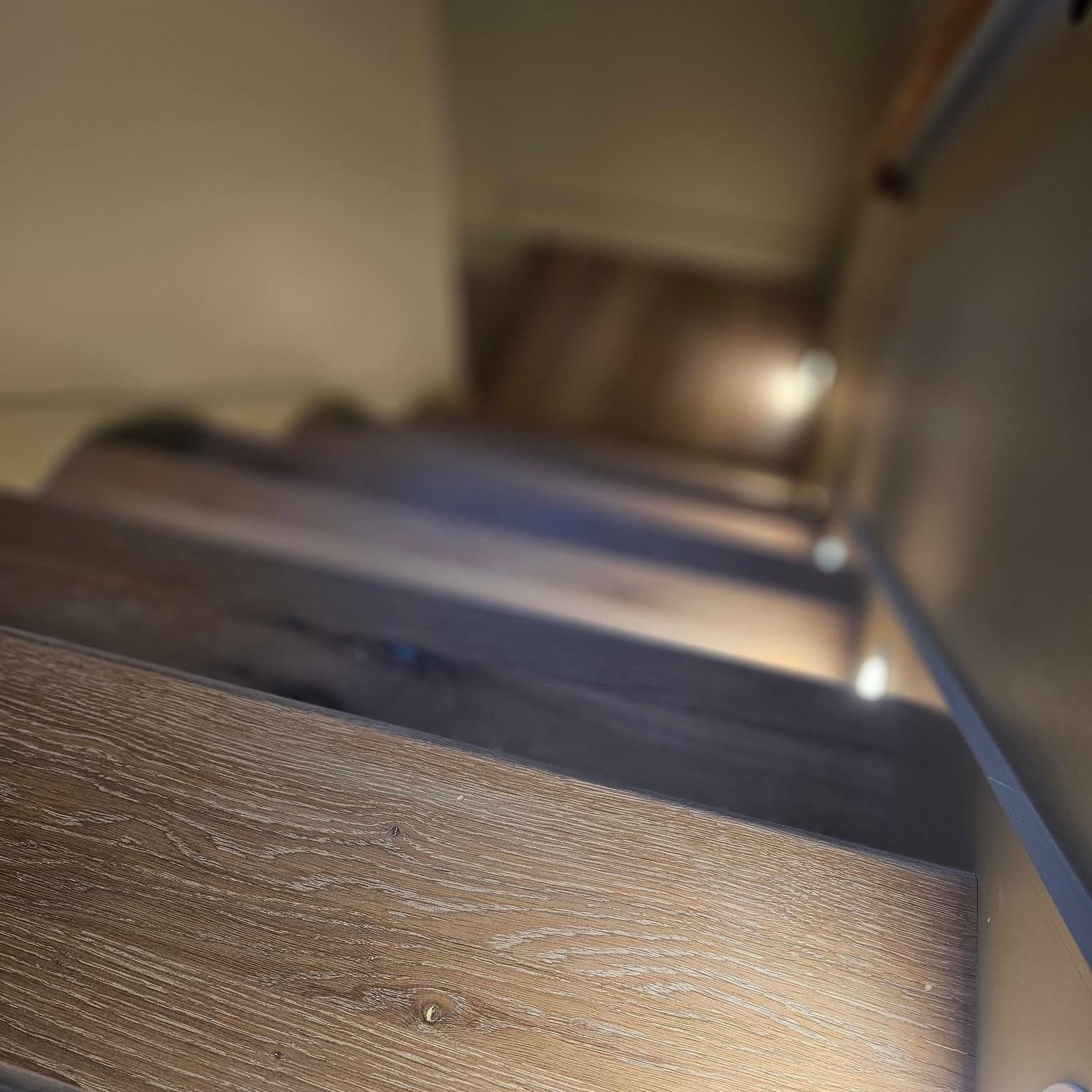 Downward shot of dark wood stairs with integrated step lights