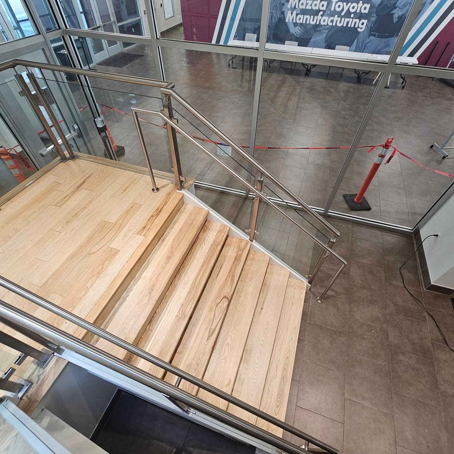High-angle look down a modern stair with light wood treads and cable railings