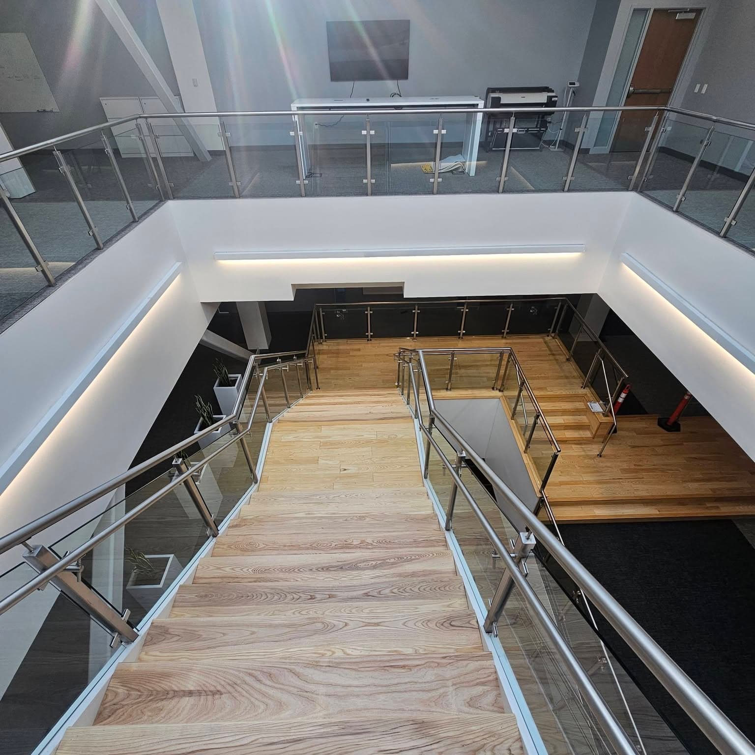 From the top of a modern stair looking down into a multi-level space