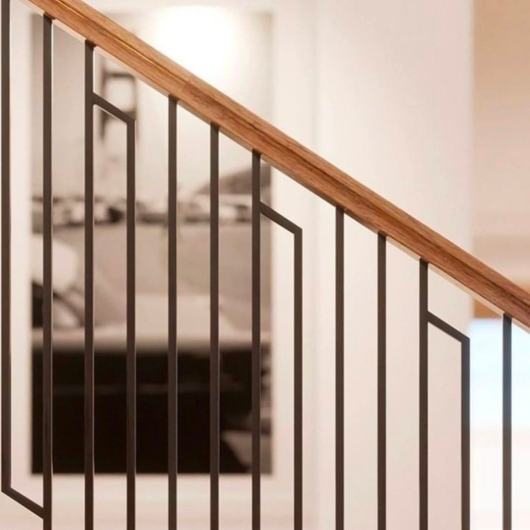 Close-up of black geometric metal balusters with a light hardwood handrail