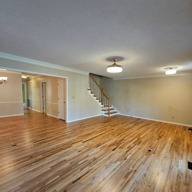Large empty room; background stair with wood treads and white risers