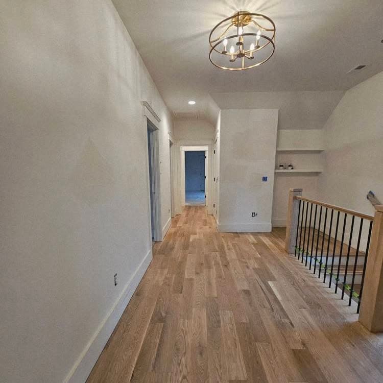 Hallway with light hardwood; wooden stair with dark balusters at far right