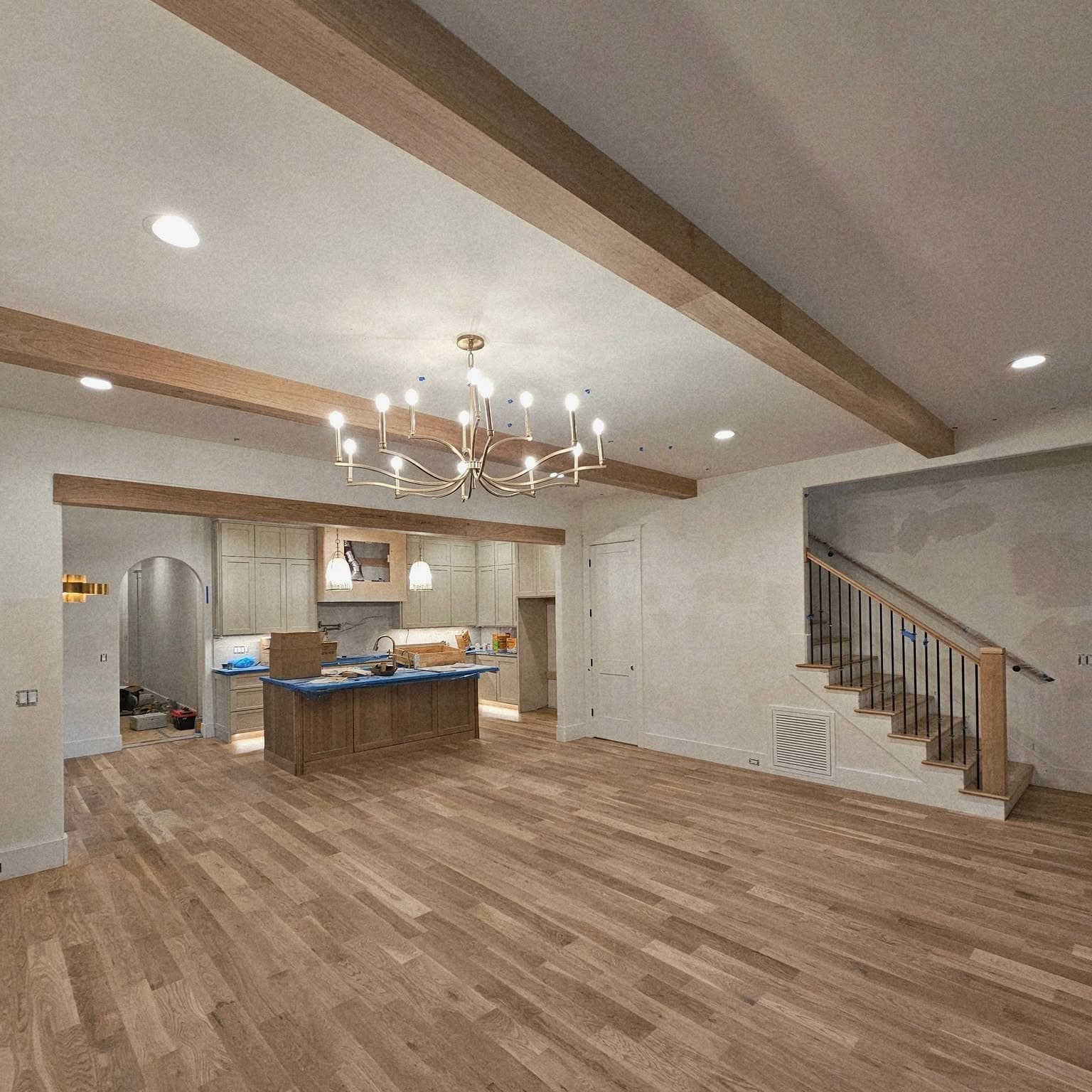 Open living area with exposed beams; wooden staircase and railing at right