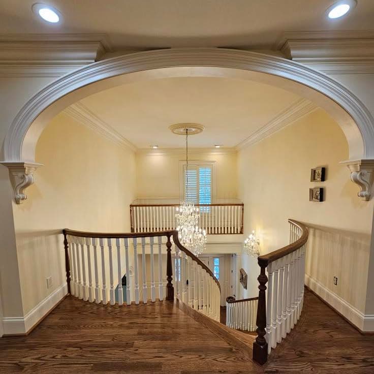 Looking down from a landing onto a curved stair with white spindles and dark handrail
