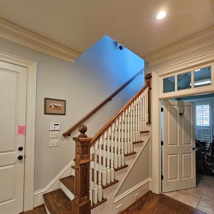 Base of a wooden stair next to an interior door, showing railing start
