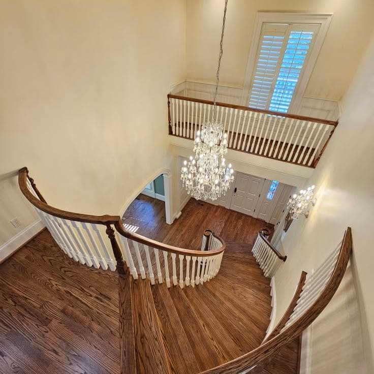 From an upper landing looking down a curved wooden stair with white spindles