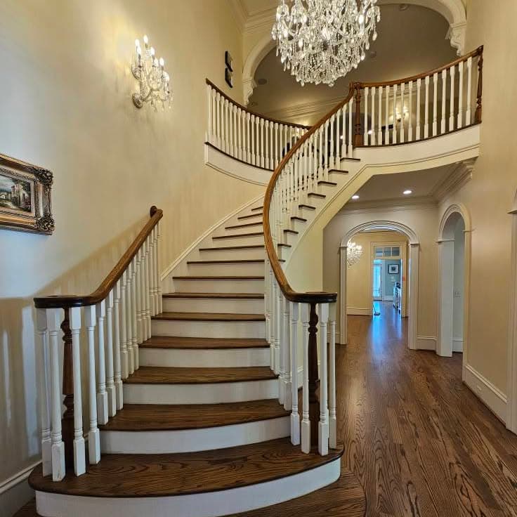 From the base of a wide curved wooden stair with white spindles