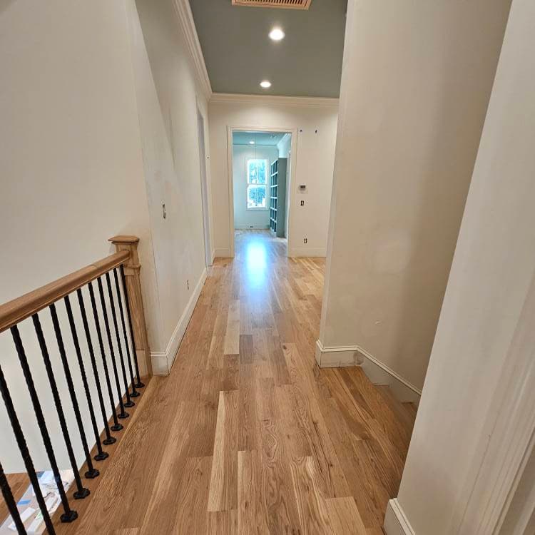 Hallway at the top of a stairwell with wooden railing at left