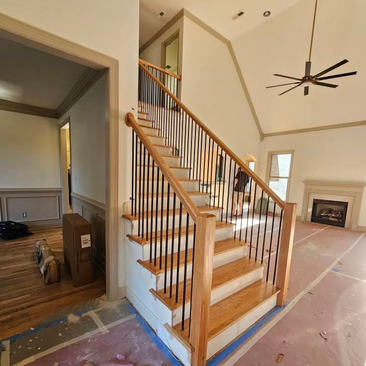 Base of a wooden stair with white risers and wood handrail
