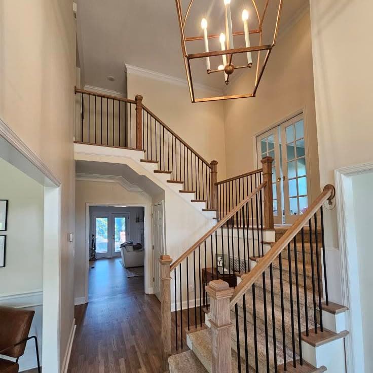 Grand foyer stair with white balusters and dark wood handrail curving at the landing