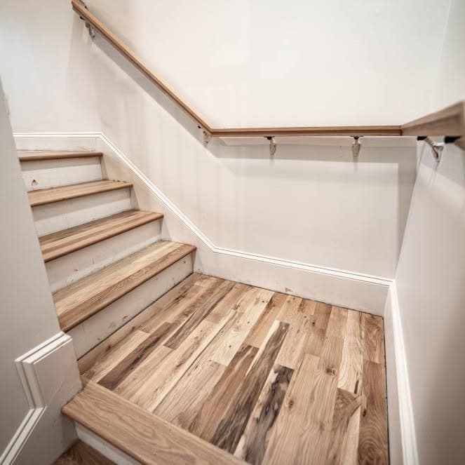 Looking up wooden stairs from a light-wood landing