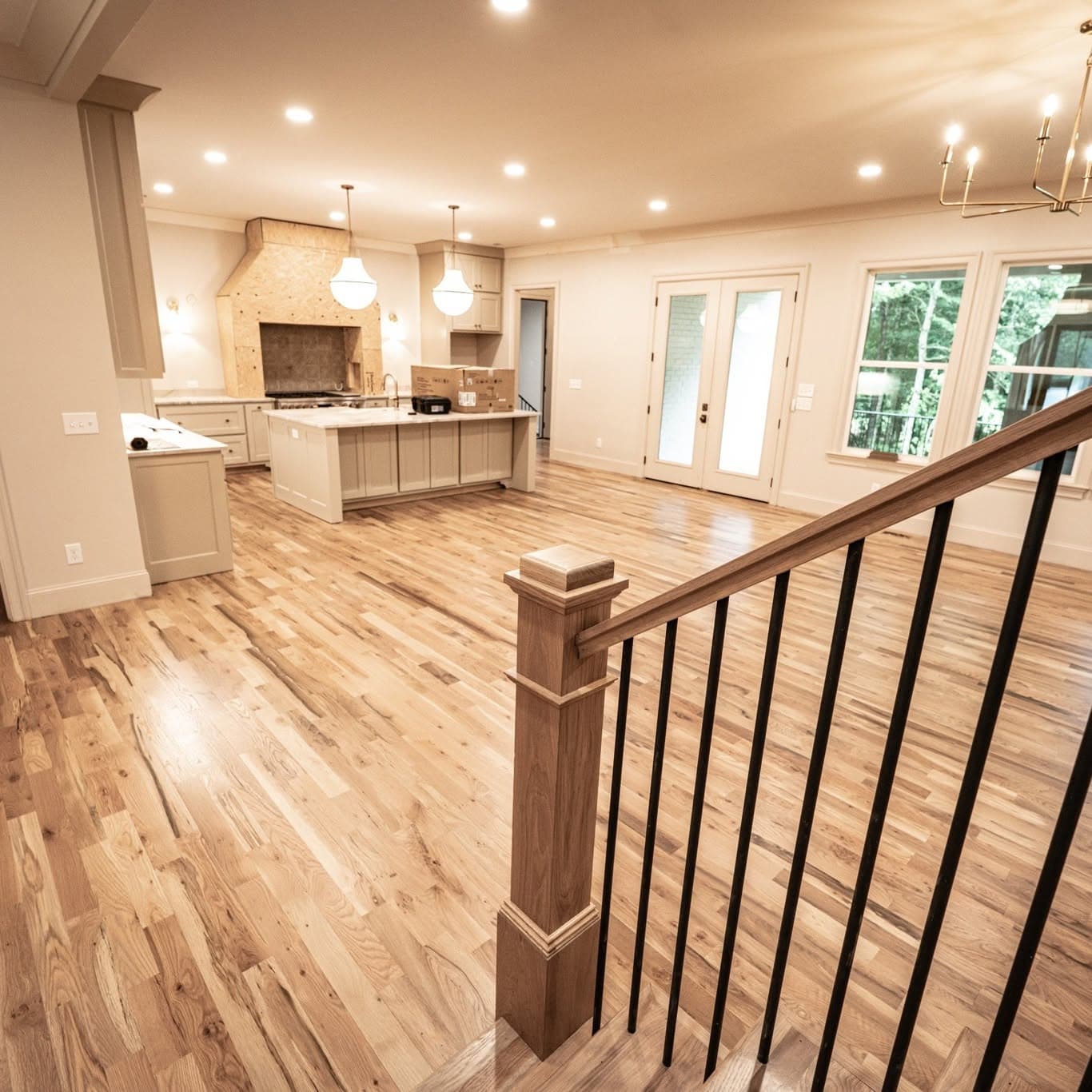 Wide wood floor leading to a stair railing that descends out of frame
