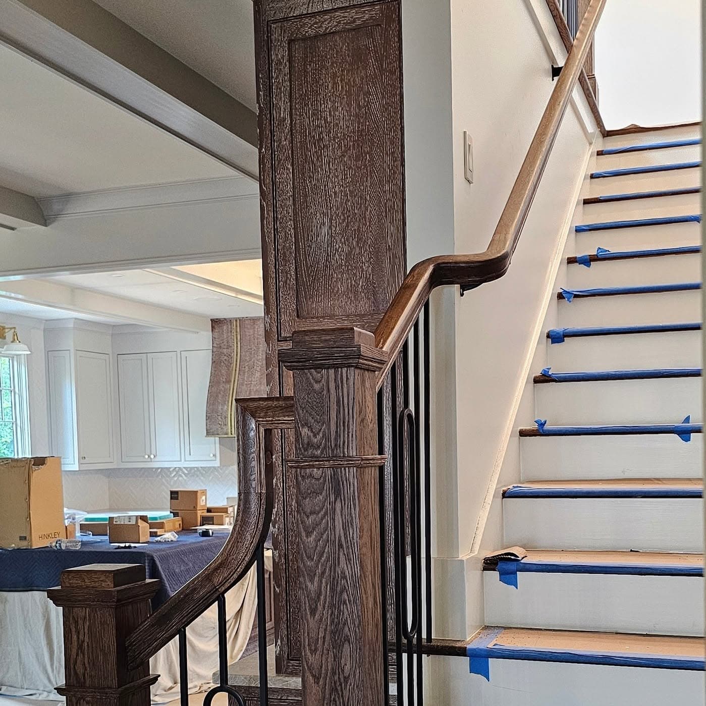 Side profile of a taped wooden stair under restoration with wood railing