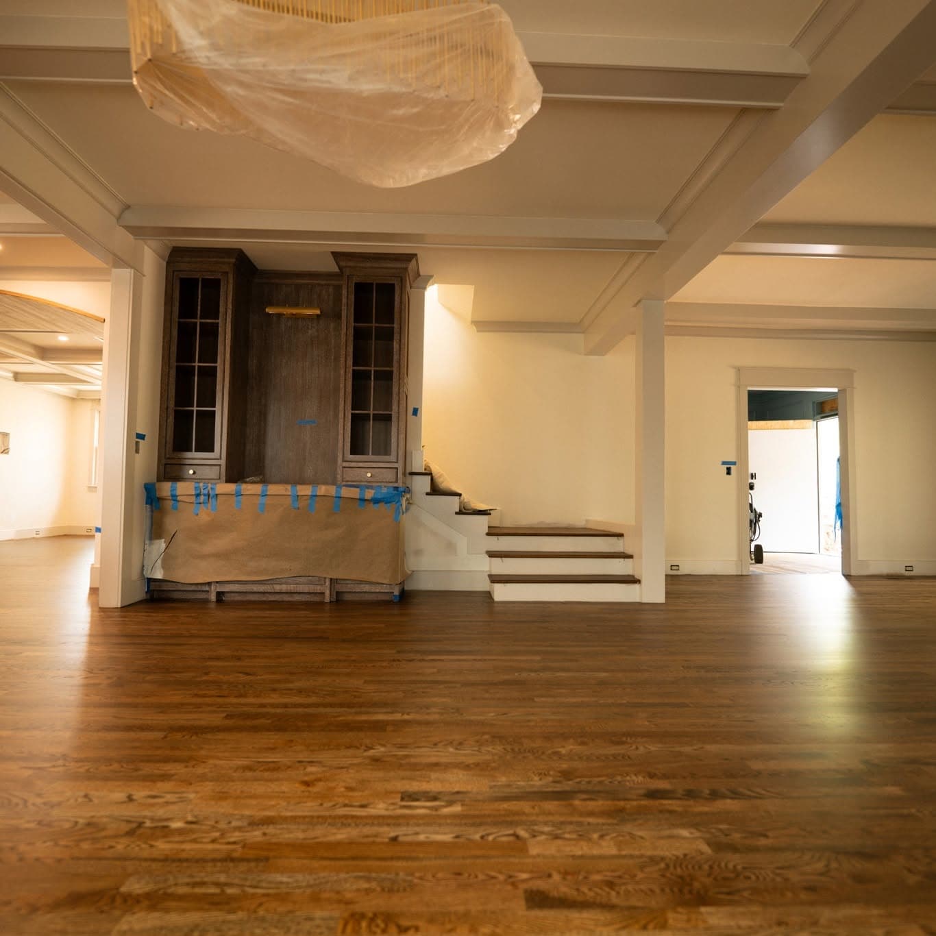 Room with coffered ceiling; bottom few dark-tread, white-riser steps before a turn