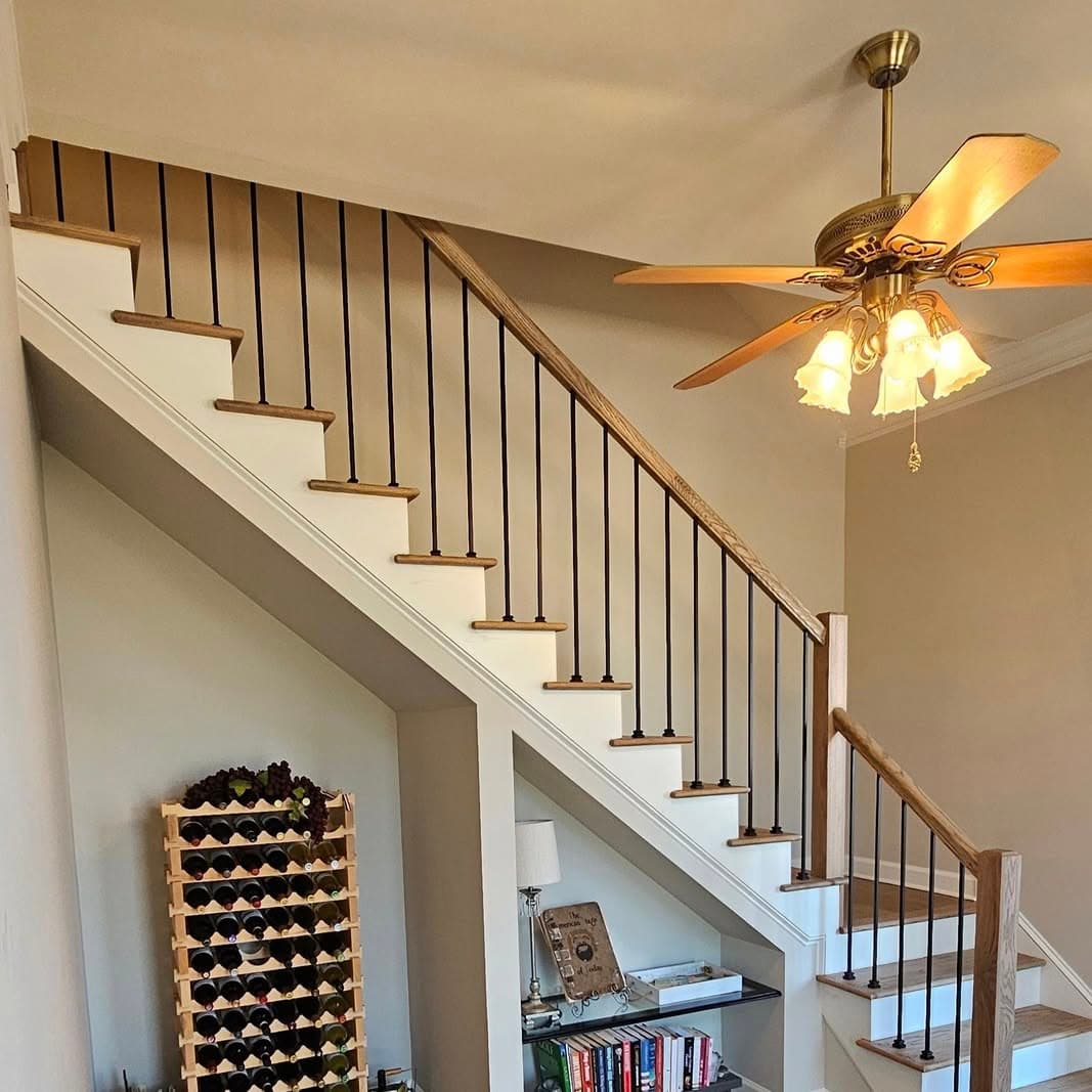 Side profile of a stair with light treads, white risers, black balusters, wine rack under