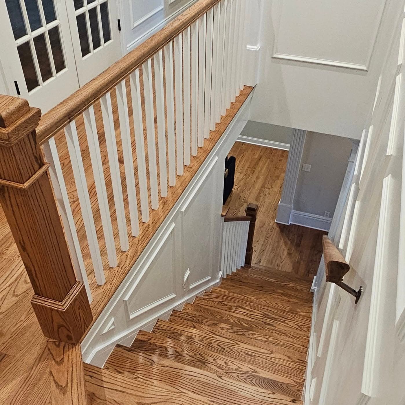 From the top looking down a landing and stair with wood handrail and white spindles