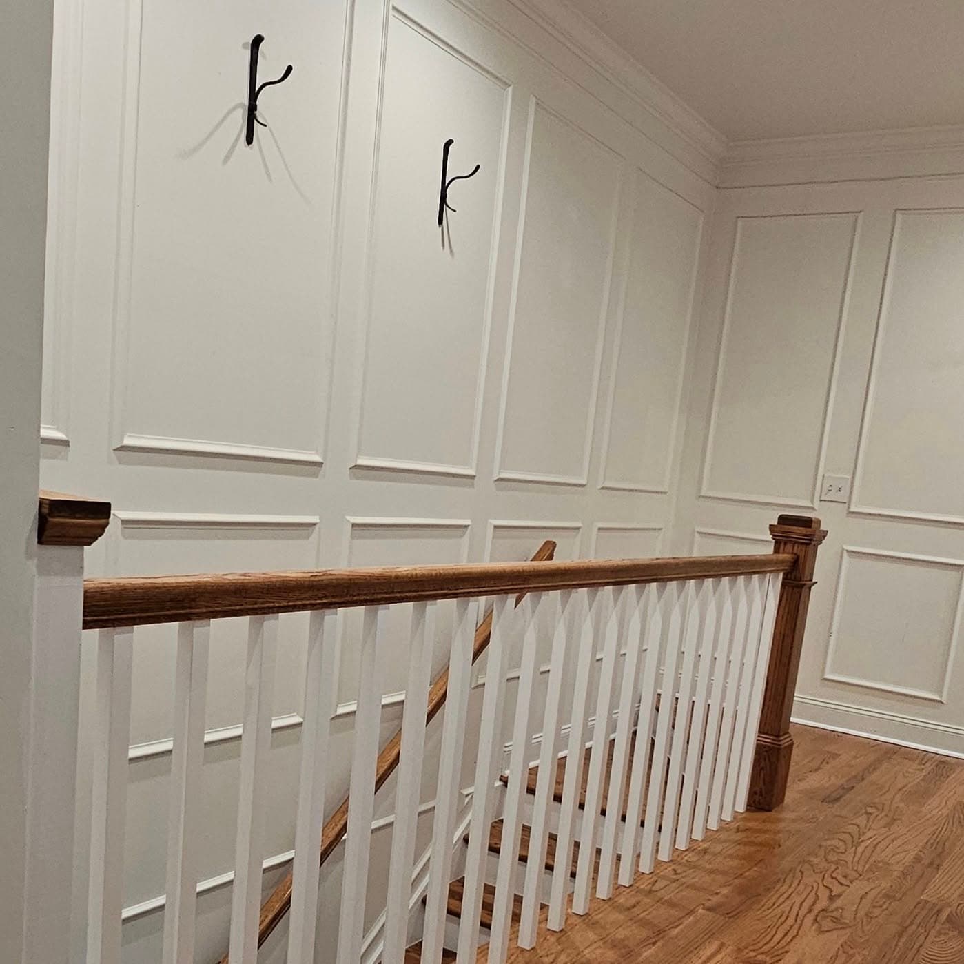 Upper landing railing with white spindles against white wainscoting