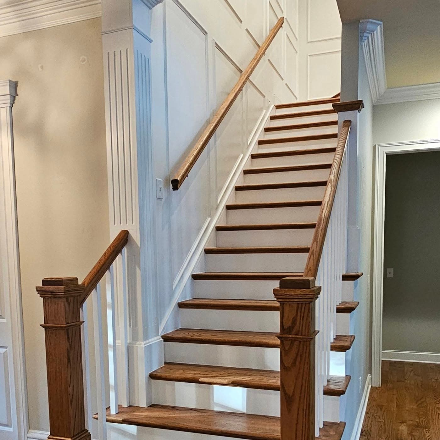 Straight-on stair with wood treads, white risers, wood handrail and white spindles