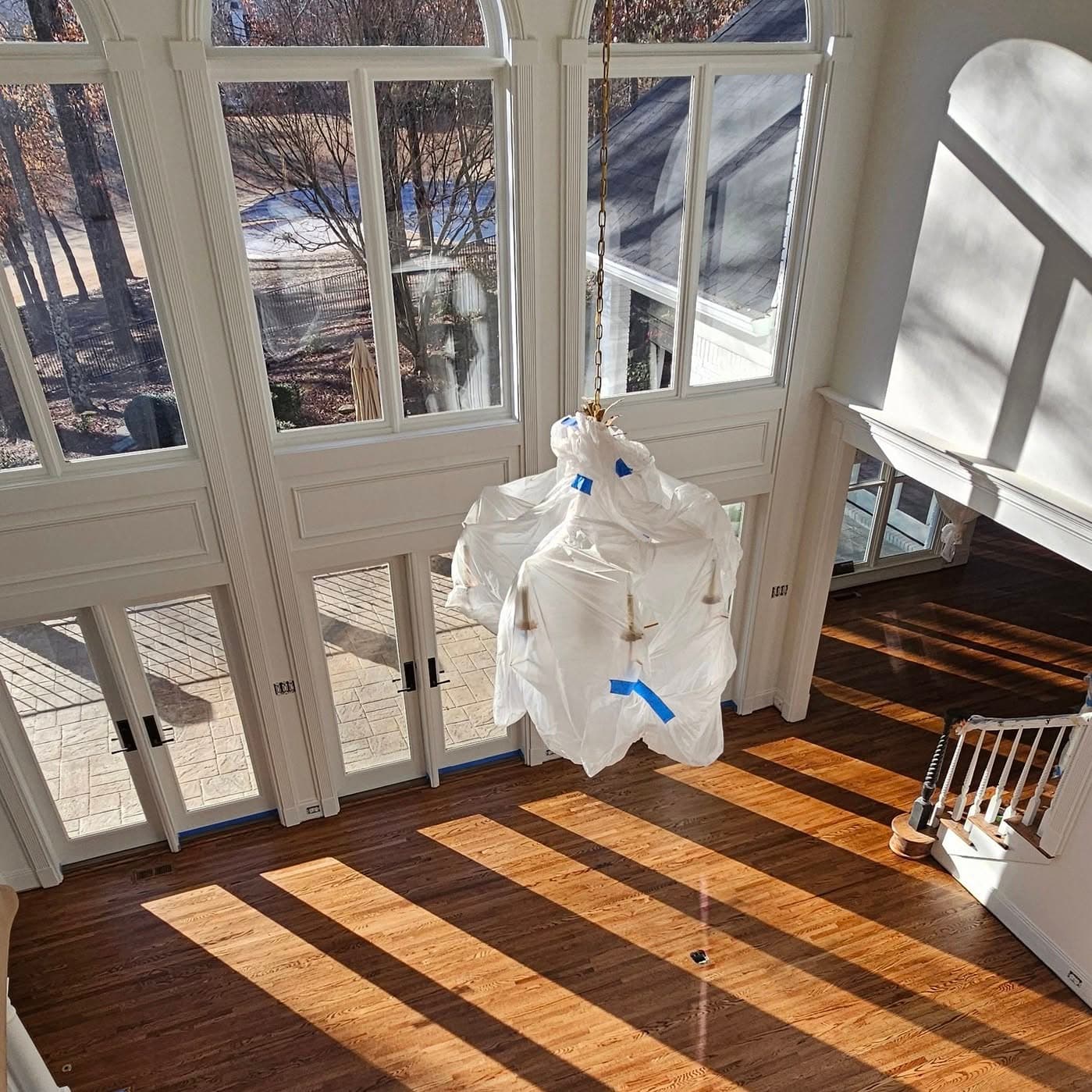 Two-story window wall; white stair railing visible at bottom right