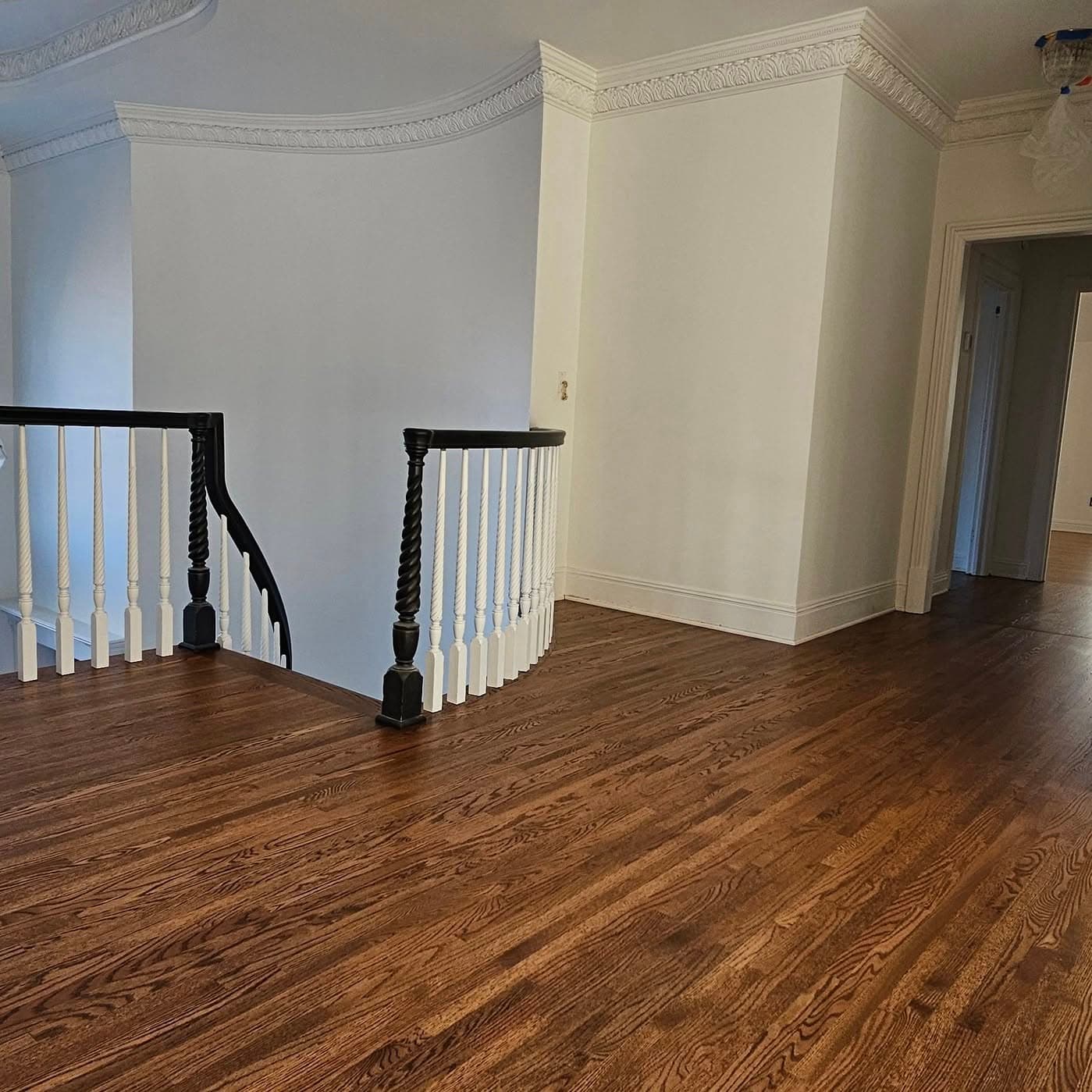 Hall landing at the top of a stair; white balusters and dark handrail turning left
