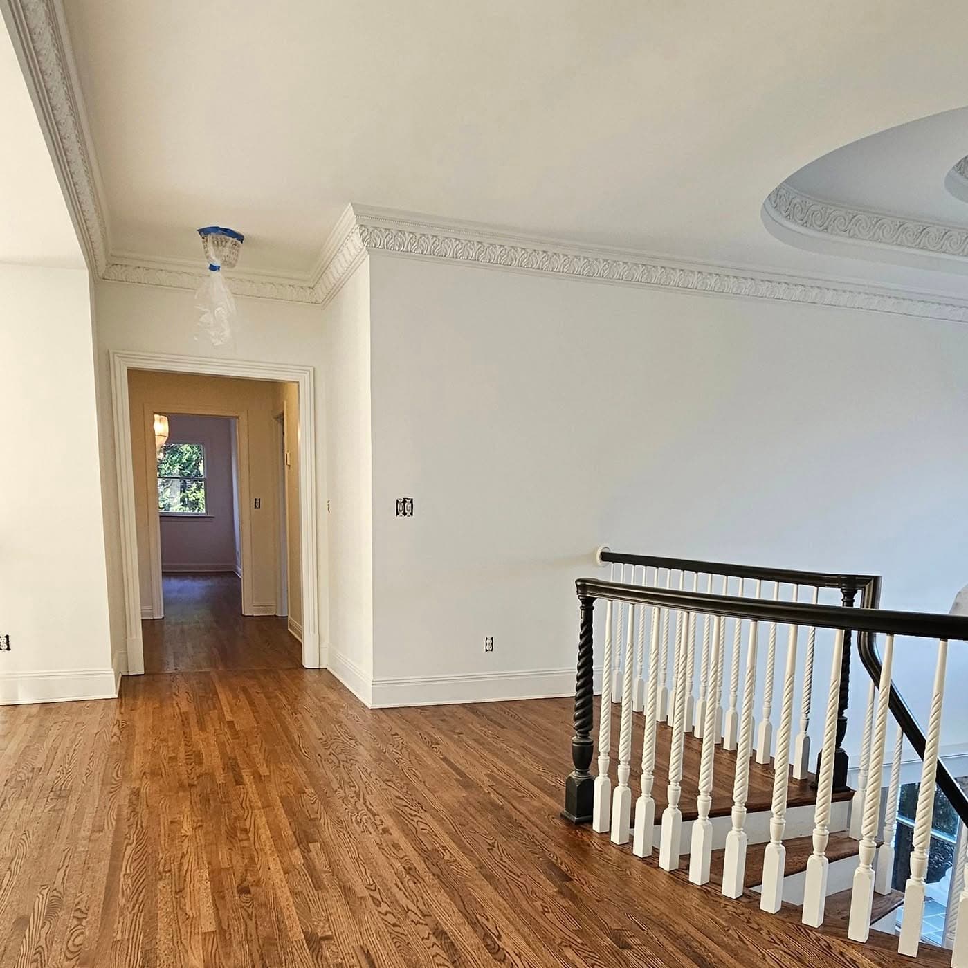 Upstairs hallway landing with white-baluster railing at right where stairs descend
