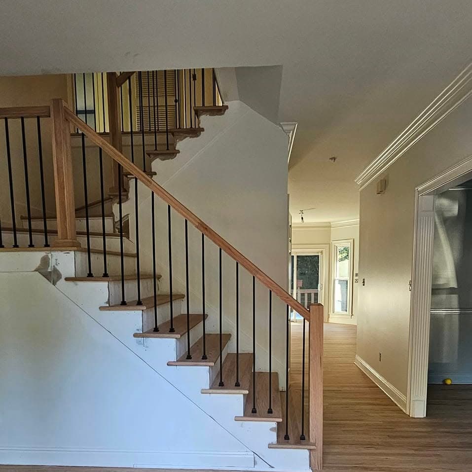 Straight wooden stair with white balusters and dark wood handrail from a hallway