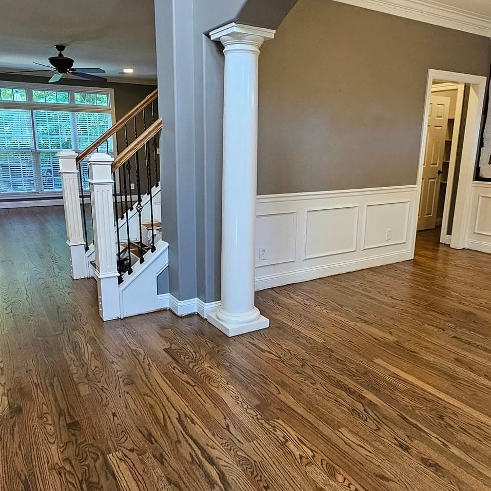 Room with white columns; white stair with wooden handrail at far left