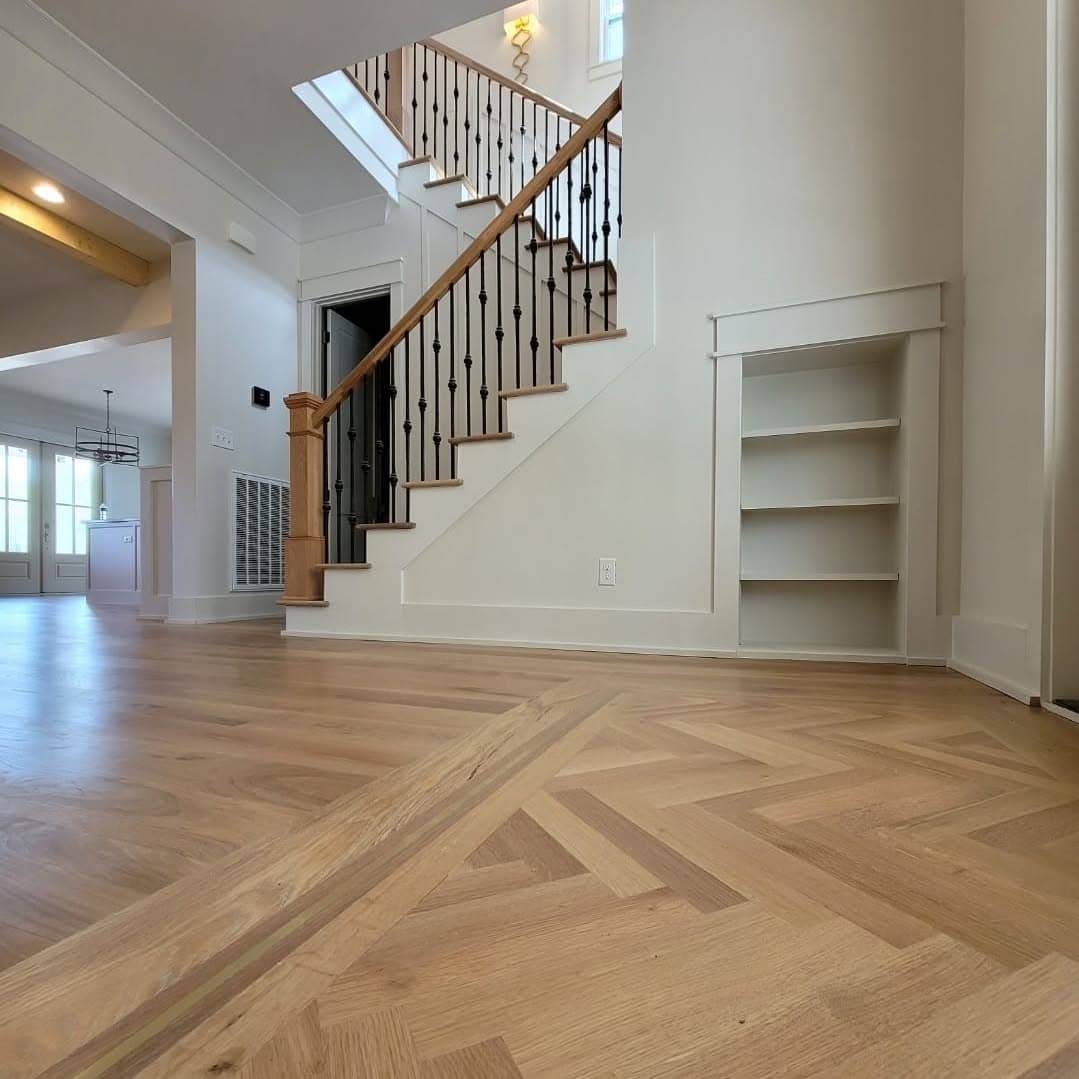 Hallway with herringbone floors; wood-tread stair with white balusters in background