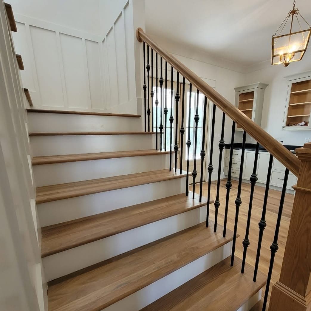 Low-angle looking up light wood stairs with dark metal balusters