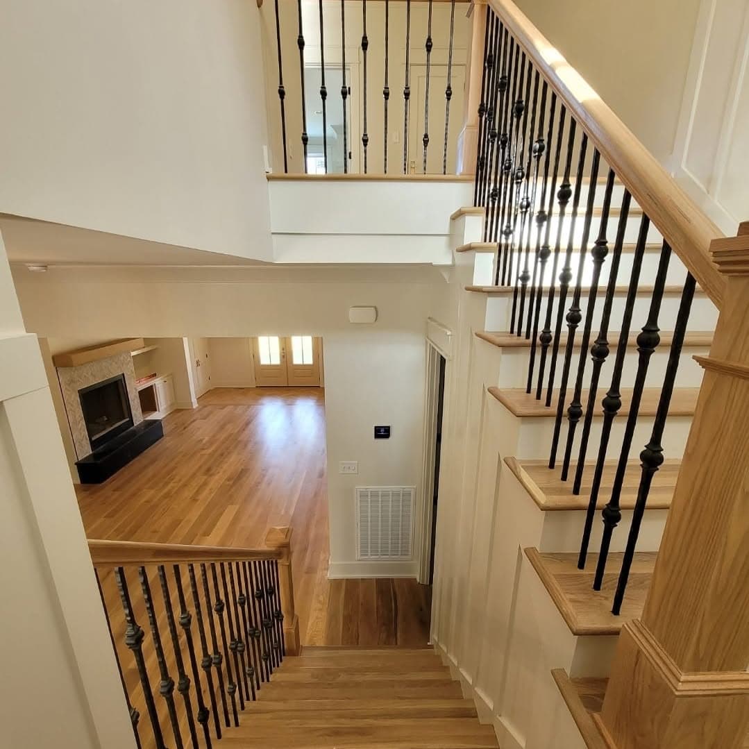 From a second-story landing looking down a wooden stair to the floor below