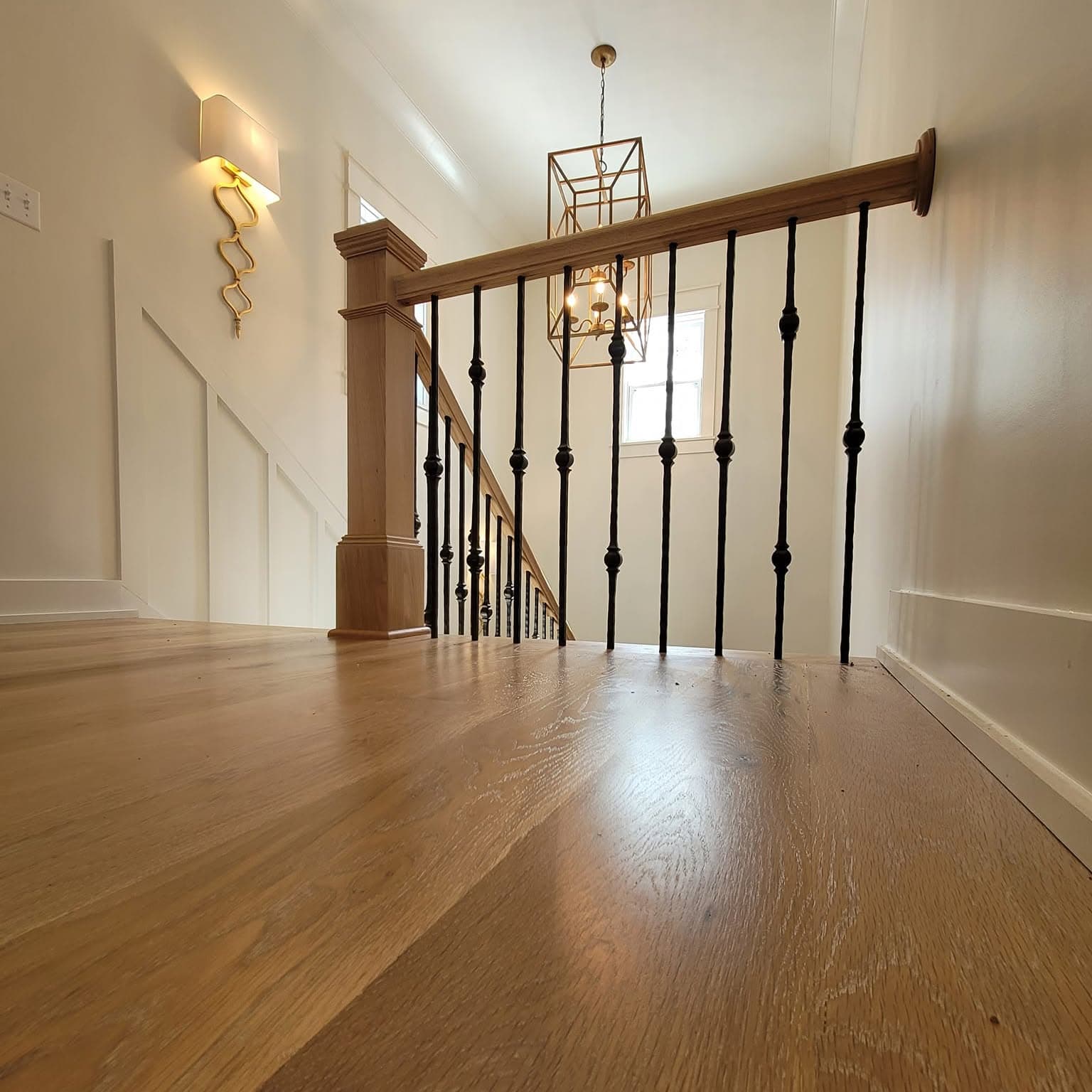 Close view of a wooden stair landing and dark metal railing