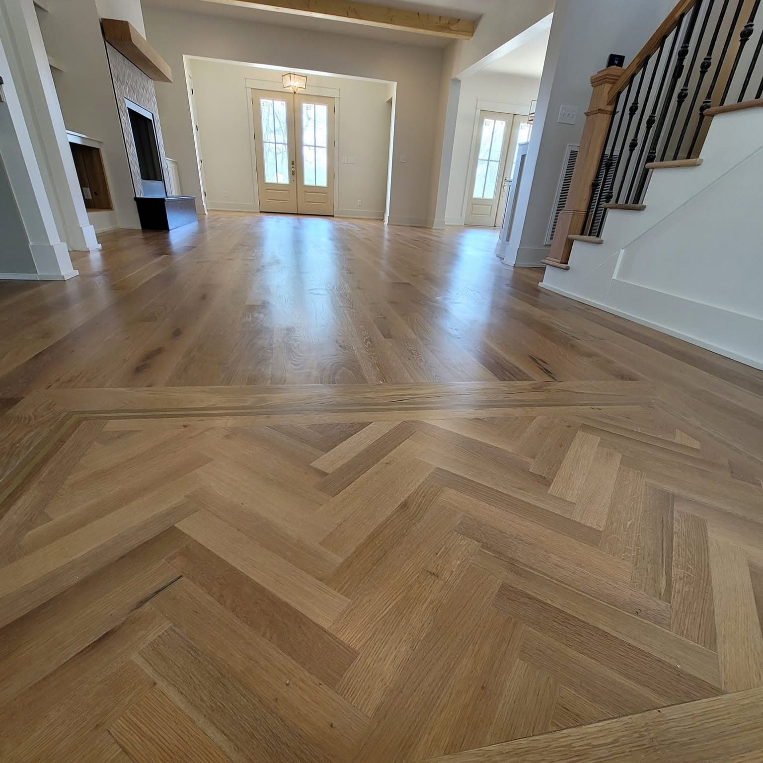 Herringbone hardwood with the bottom of a staircase visible at right