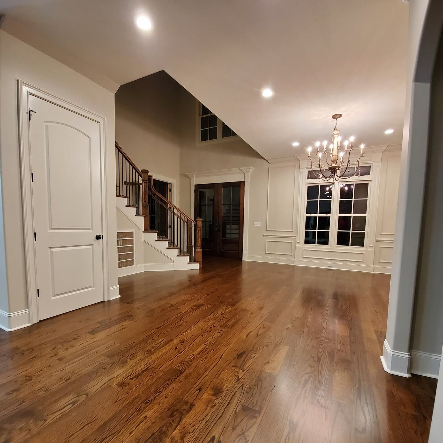 Dark-stained foyer; background stair with dark wood treads and white spindles