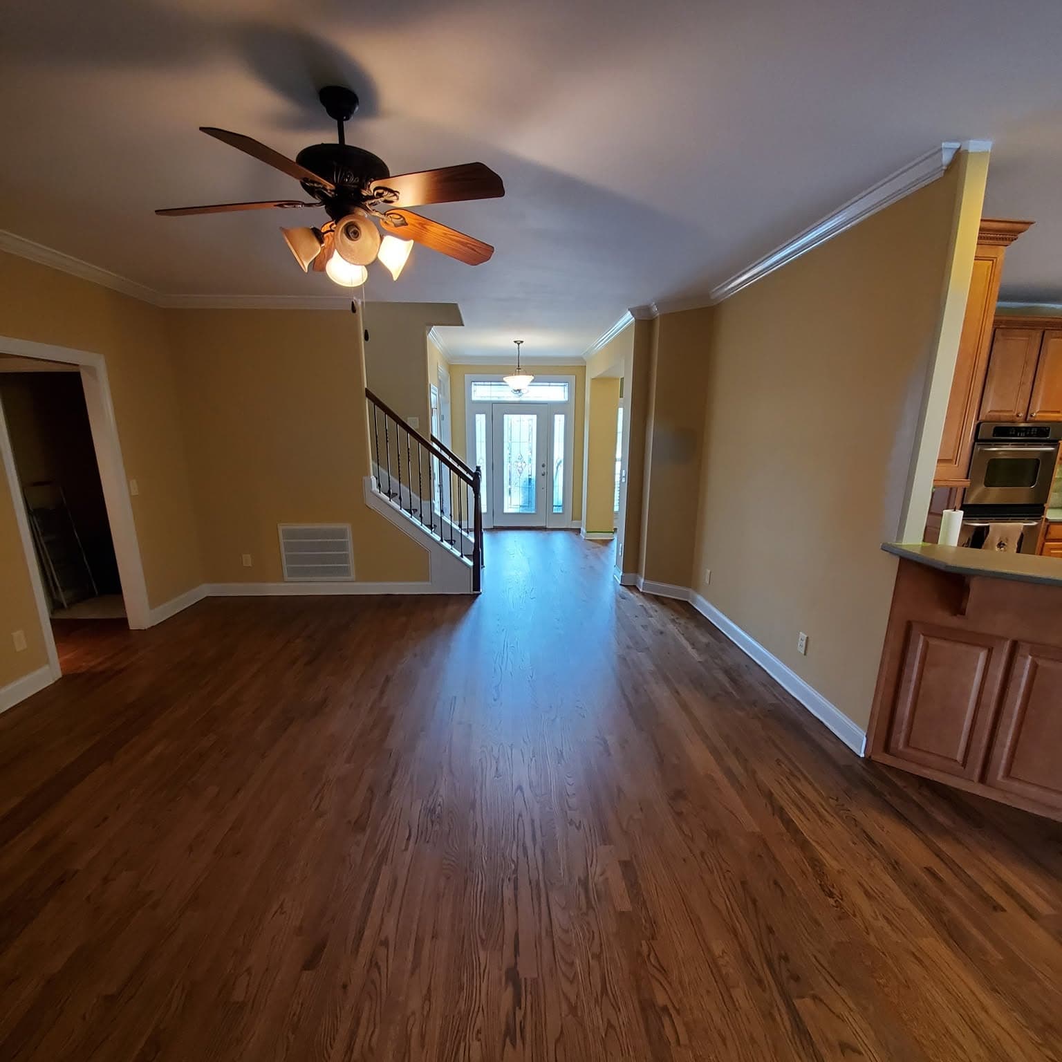 Hallway with polished hardwood; stair with white spindles and dark handrail at left