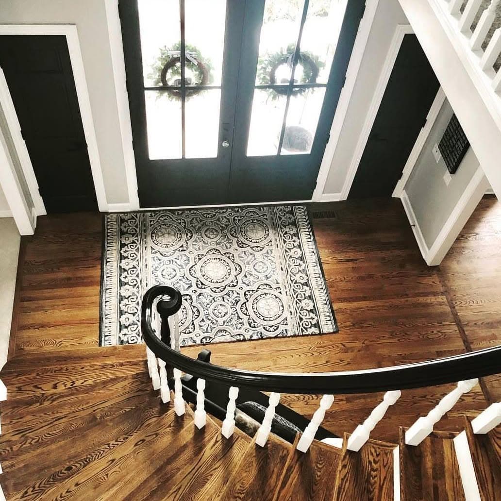 High-angle from a landing: curved stair with black handrail and white spindles