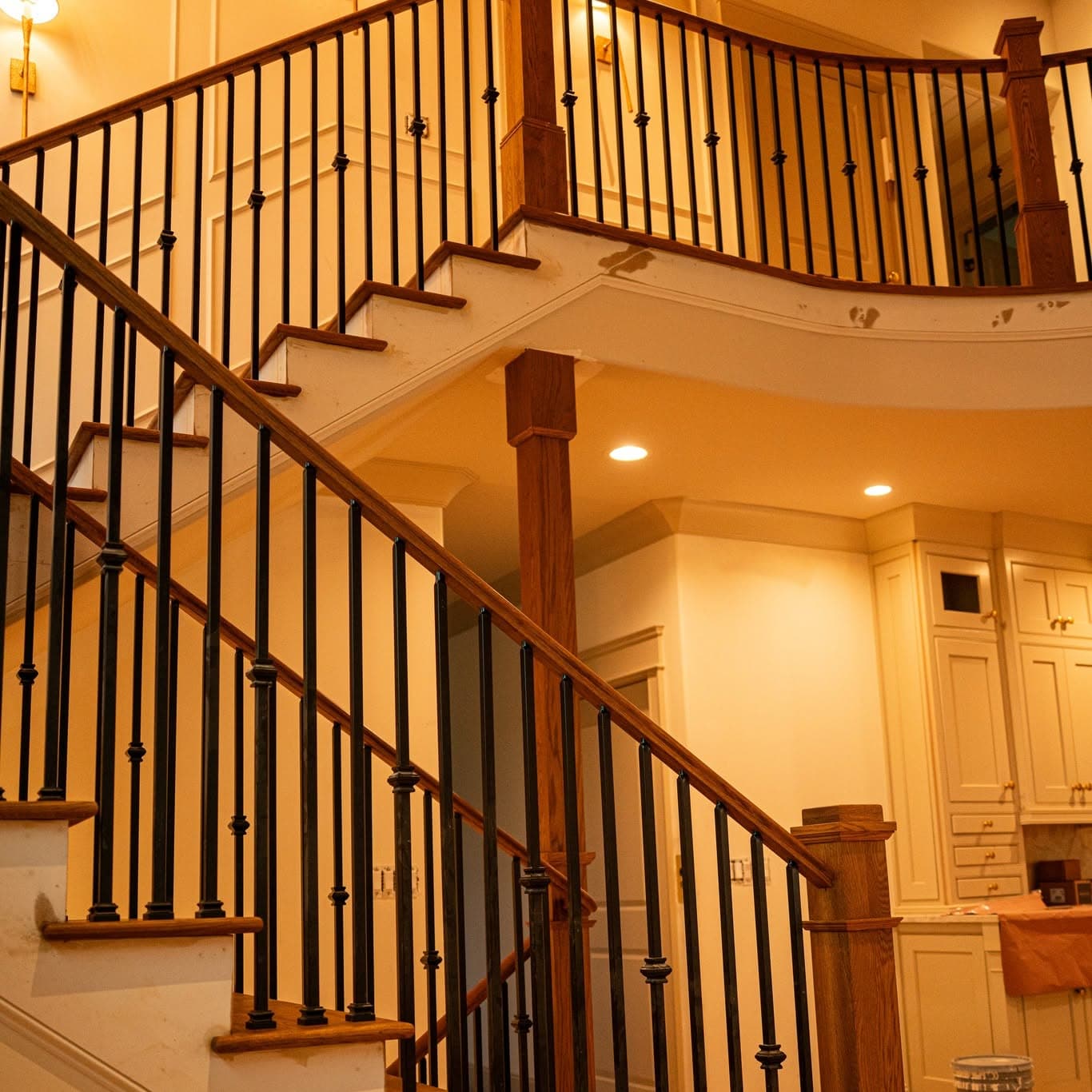 Curved hardwood staircase and upper balcony with oak treads, white risers, and black metal balusters — a job by Rocket City Stairs