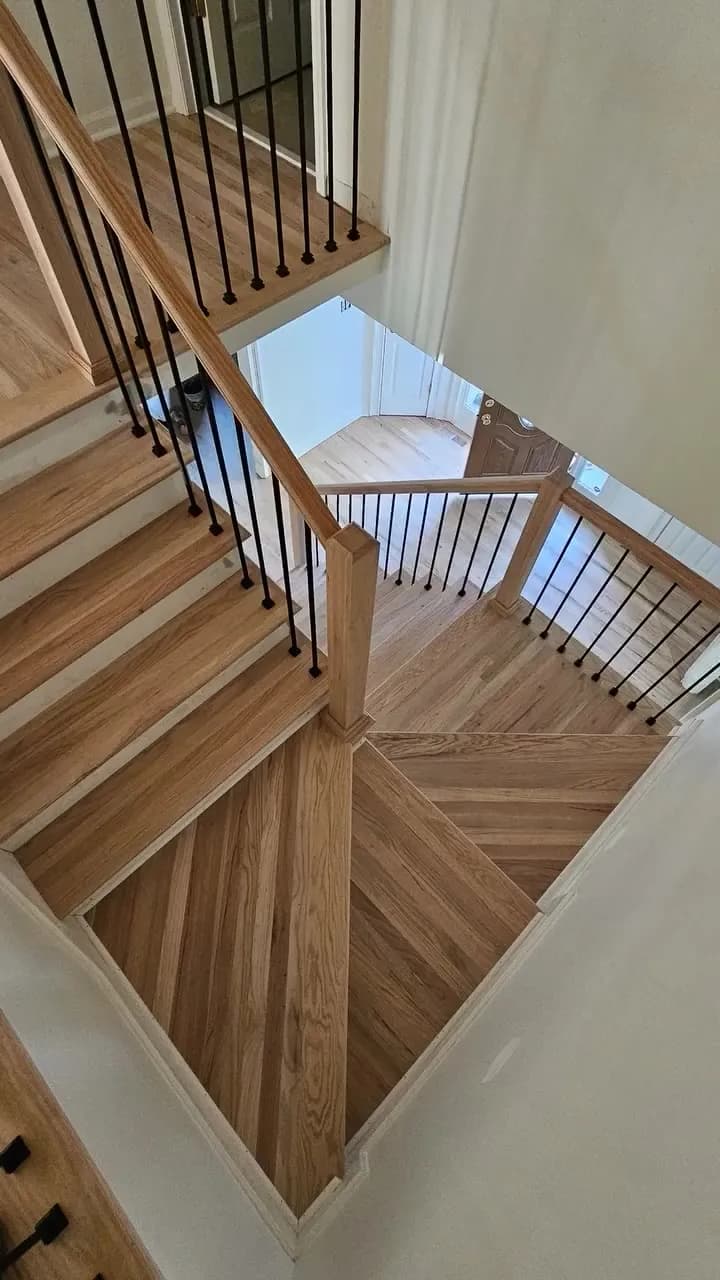 After: looking down a finished oak Huntsville staircase and landing with white risers and matte black balusters